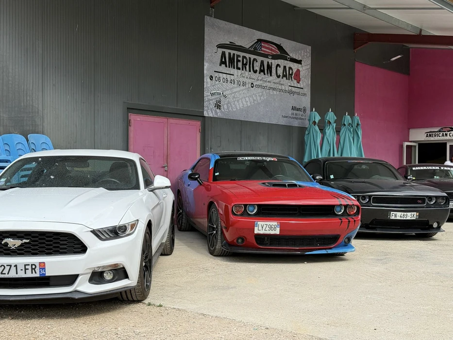 Showroom automobile extérieur avec véhicules américains exposés devant garage