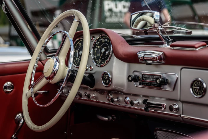 Intérieur showroom automobile avec vendeur en chemise blanche remettant clés de voiture à couple souriant, homme en polo noir et femme en chemise blanche, devant véhicule rouge