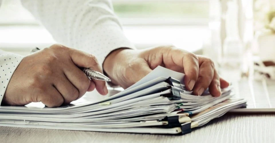 Espace de travail administratif avec documents commerciaux étalés sur surface claire