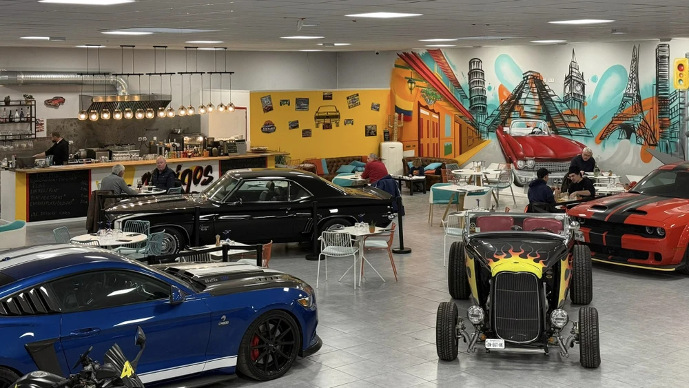 Scène extérieure avec pickup rouge RAM garé sur parking béton, mur gris en arrière-plan, végétation et ciel bleu