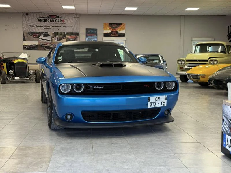 Extérieur d'un garage automobile spécialisé avec deux Dodge Challenger stationnées devant l'enseigne "American Car"
